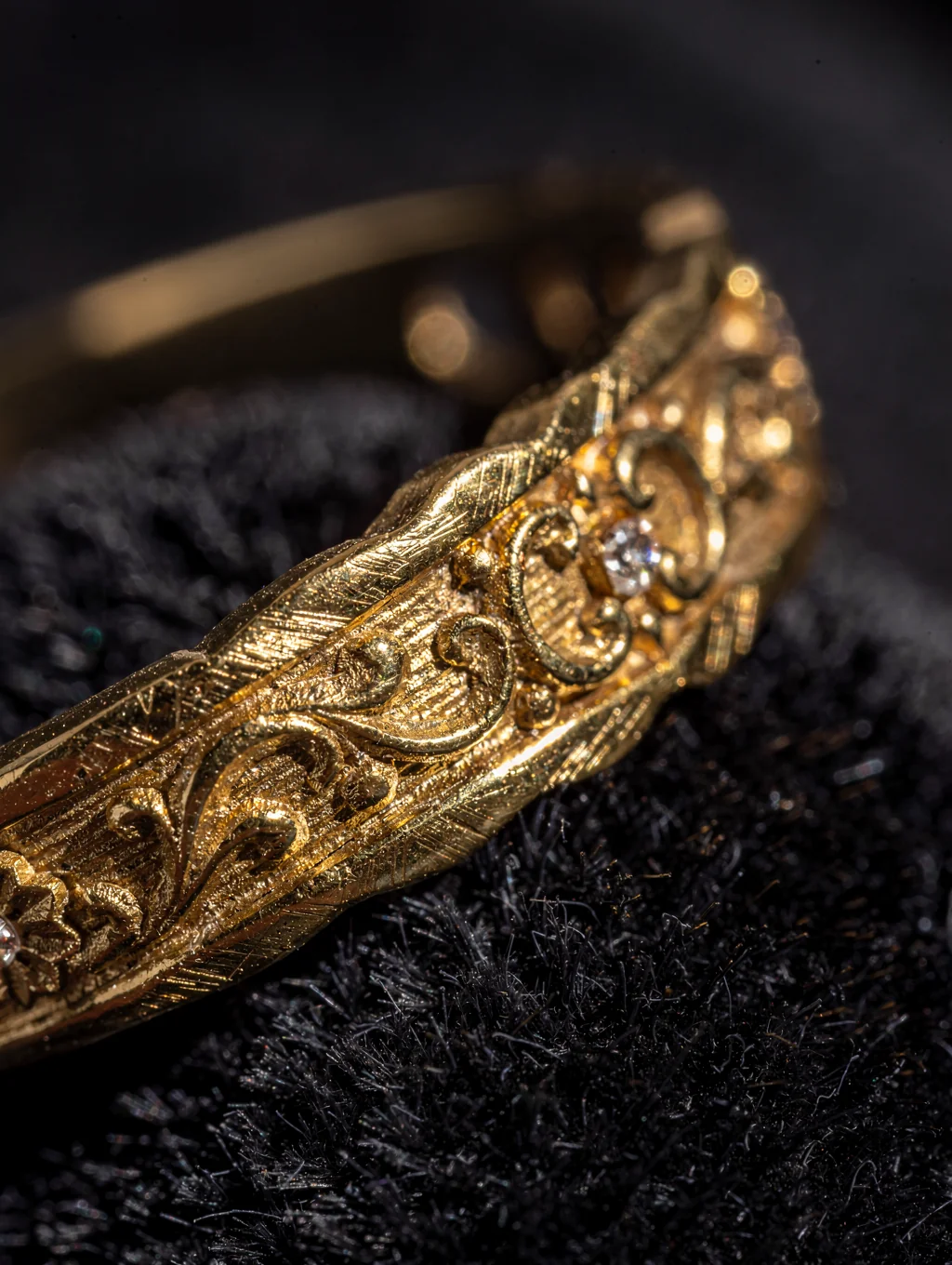 Extreme macro close-up of emerald-cut gemstone bezel setting and hand-engraved gold metal texture